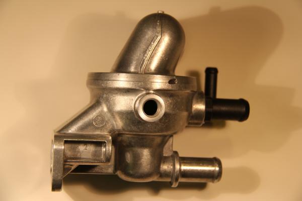 PHOTO OF ONE SIDE VIEW OF THE ORIGINAL EQUIPMENT ENGINE THERMOSTAT ASSEMBLY